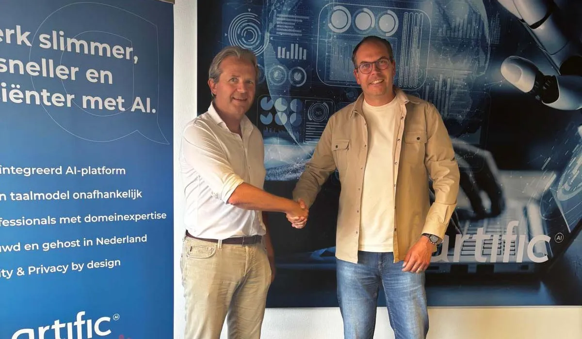 Edwin van Buren et Ivo Rupert se serrent la main devant une bannière d’Artific et une impression murale représentant une main robotique.